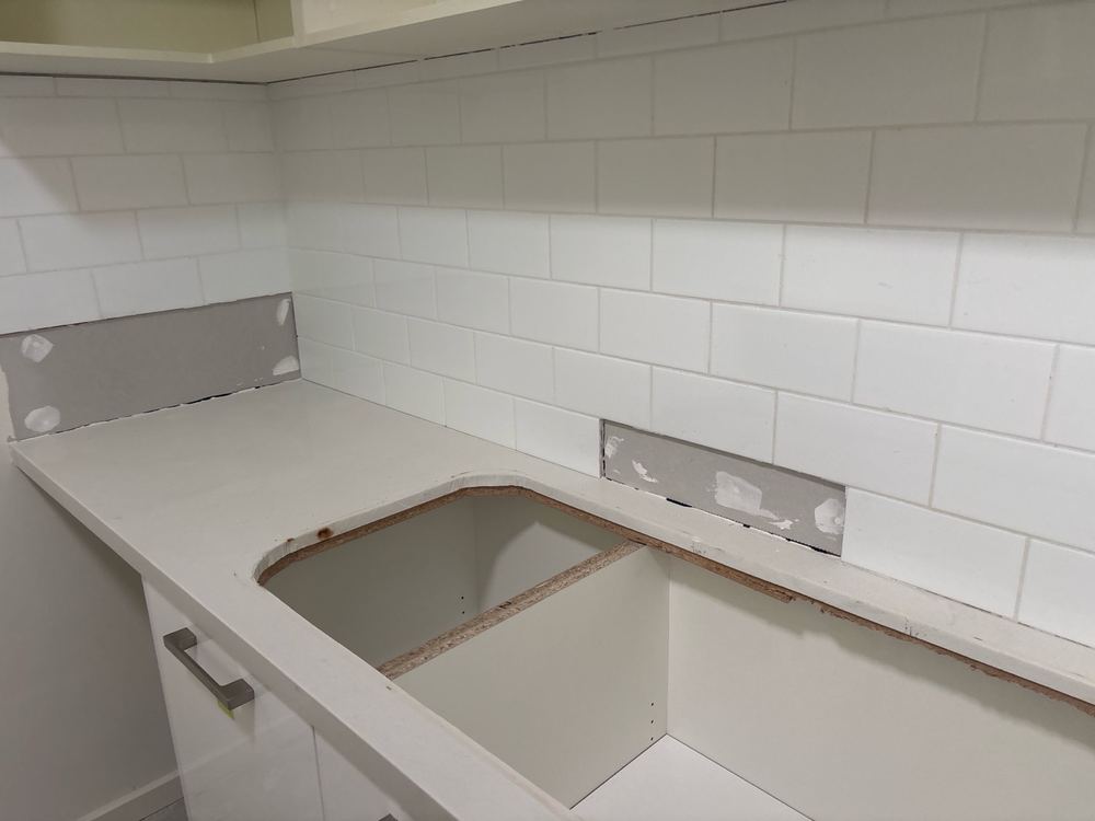 Splashback tiles removed and patched with plaster without proper joints, found during a defect investigation inspection in Derrimut