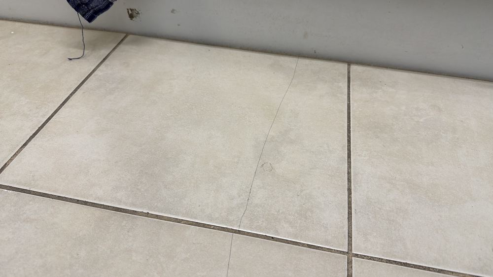 Broken tile in a wet area that needs replacing, found during a pre-purchase inspection in Deer Park